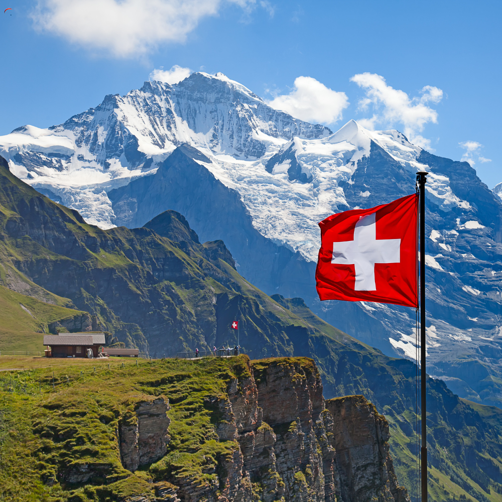 swiss landscape with mountains, snow, blue sky and a swiss flag